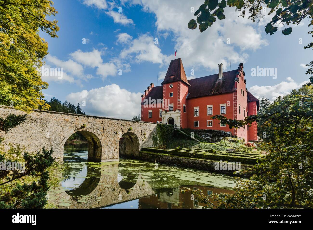 Cervena Lhota, Repubblica Ceca - 28 Settembre 2019: vista del famoso castello rosso permanente sulla roccia al centro del lago con il ponte di pietra in tutta l'acqua. Foto Stock