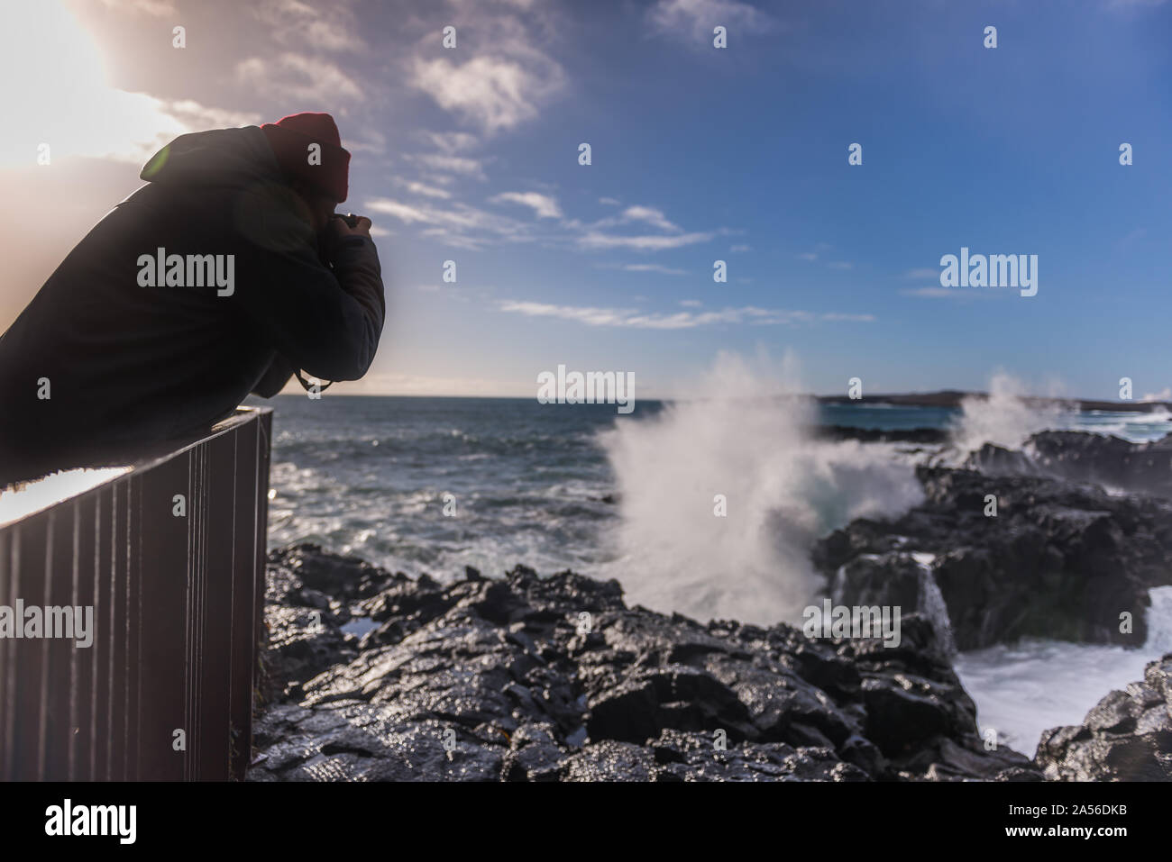 Tourist fotografare le onde del mare dal molo, Reykjanes, Islanda Foto Stock