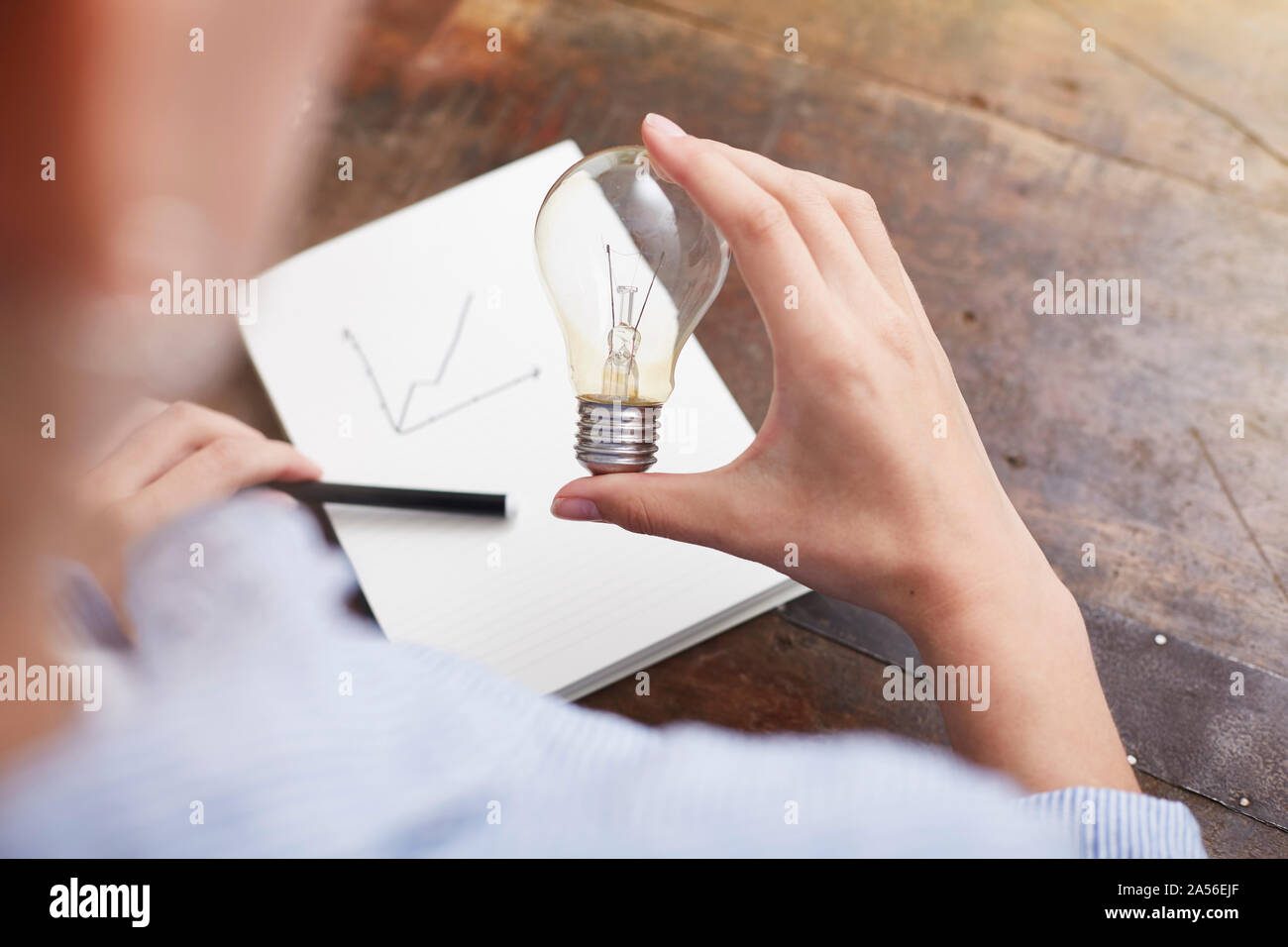 Donna con la lampadina elettrica pianificazione modo per risparmiare energia e denaro Foto Stock