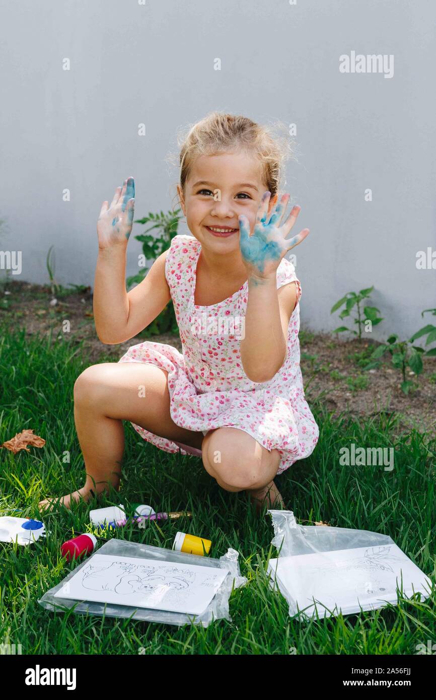 Felice bambina gioca con vernice in giardino Foto Stock