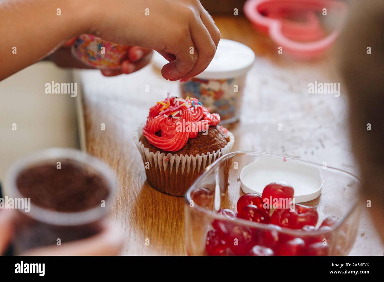 Mano di colore gocciolamento spruzza sul cupcake Foto Stock
