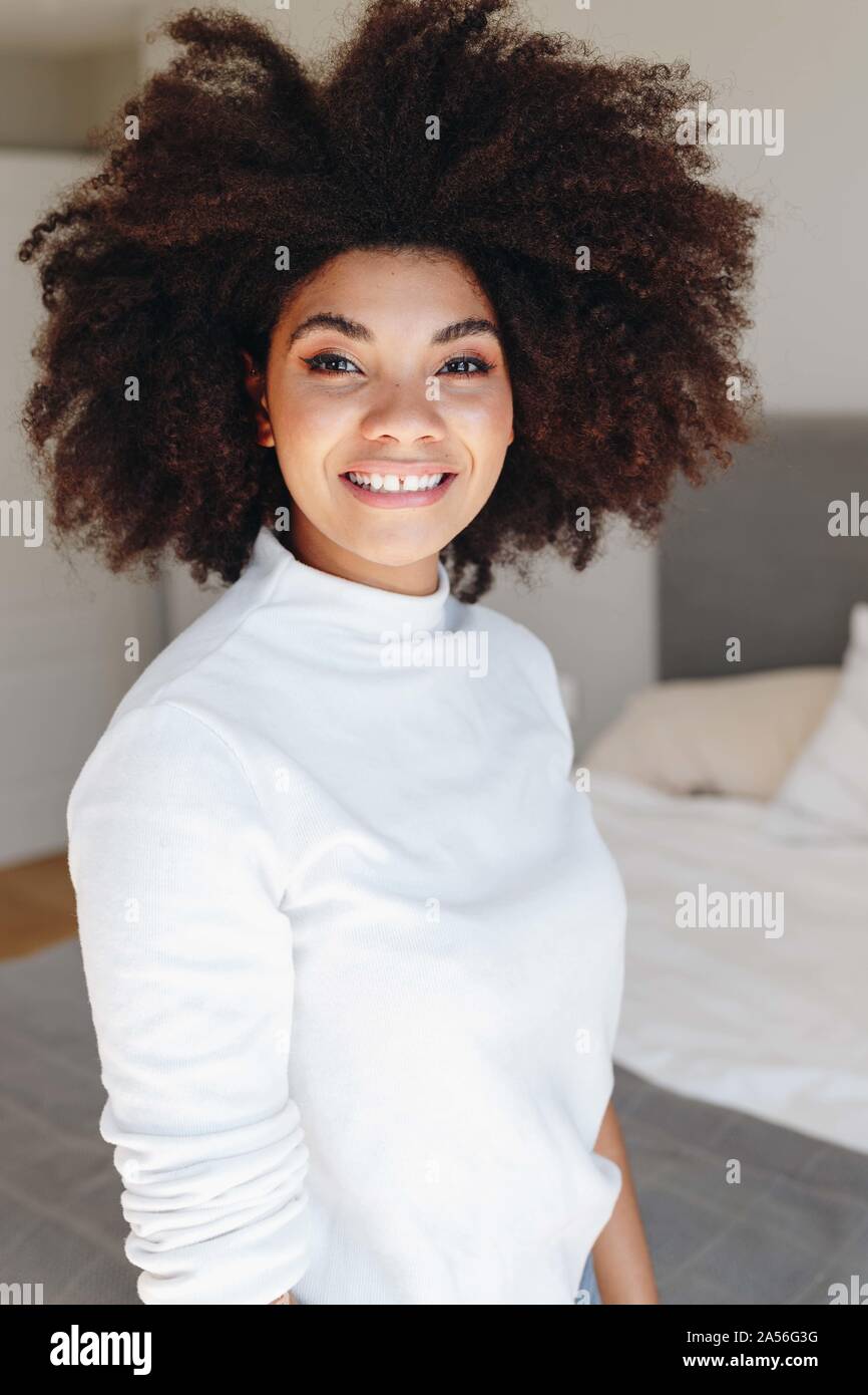 Felice giovane donna con acconciatura afro in camera da letto, vita ritratto Foto Stock