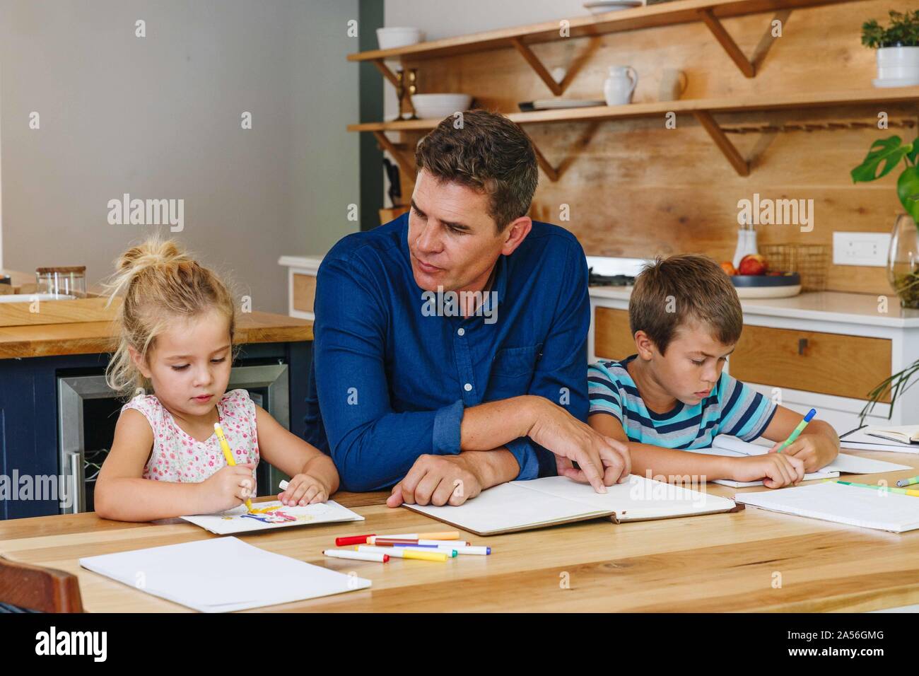 Padre aiutando i bambini con i compiti a casa Foto Stock