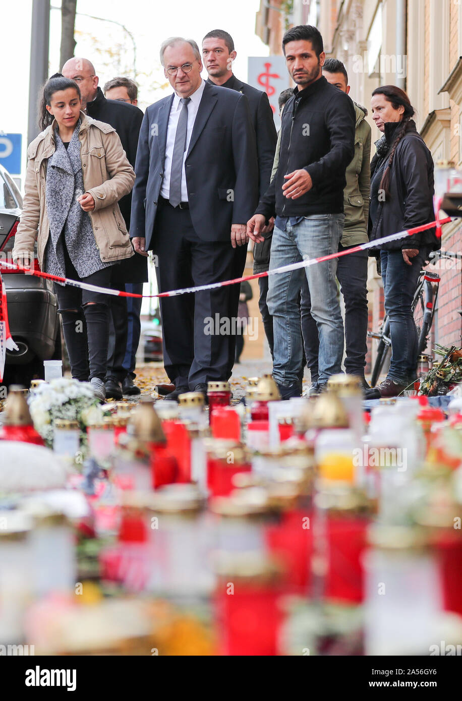 18 ottobre 2019, Sassonia-Anhalt, Halle: Reiner Haseloff (quarta da sinistra, CDU), il primo ministro del Land Sassonia-Anhalt, e Izzet Cagac (terzo da destra), l'operatore della Kiez Döner Kebab, posizionarsi di fronte al di fiori e candele nella parte anteriore del negozio. Haseloff e il governo federale il Commissario per le vittime hanno visitato il Kiez-Döner, che è stata colpita da destra attacco terroristico. Entrambi hanno assicurato il proprietario dello snack bar e i suoi collaboratori del loro supporto. Il 9 ottobre il tedesco Stephan B., pesantemente armati, aveva tentato prima di penetrare in una sinagoga. Quando il suo piano non riuscita ha girato un 40-anno Foto Stock