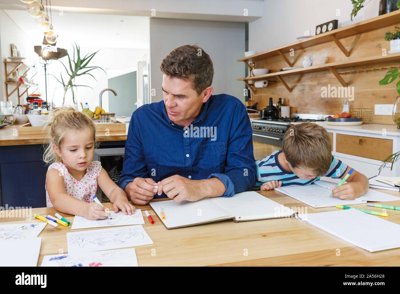 Padre aiutando i bambini con i compiti a casa Foto Stock