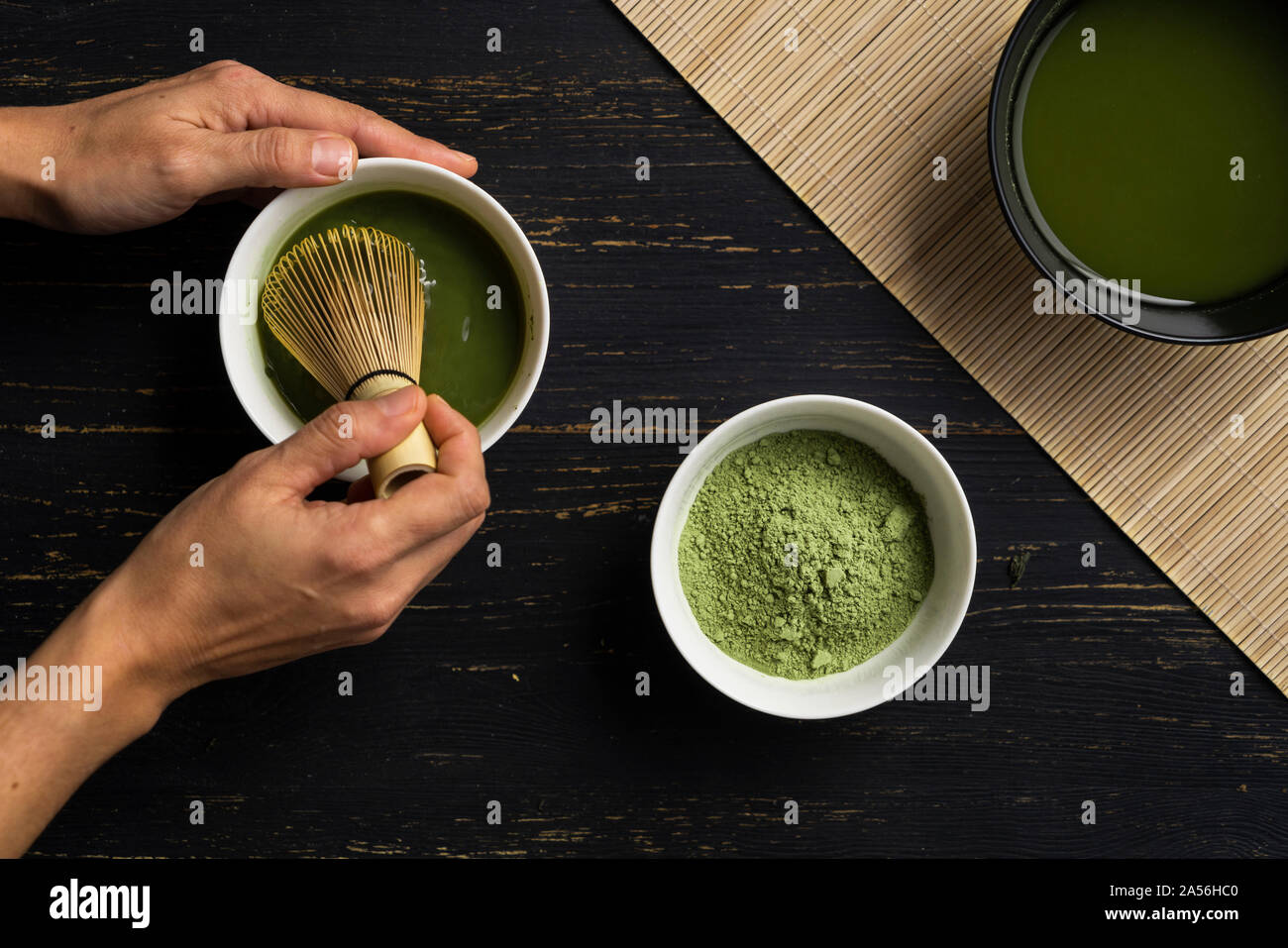 Donna con le mani in mano la miscelazione di tè verde Matcha in polvere in una ciotola, vista aerea Foto Stock