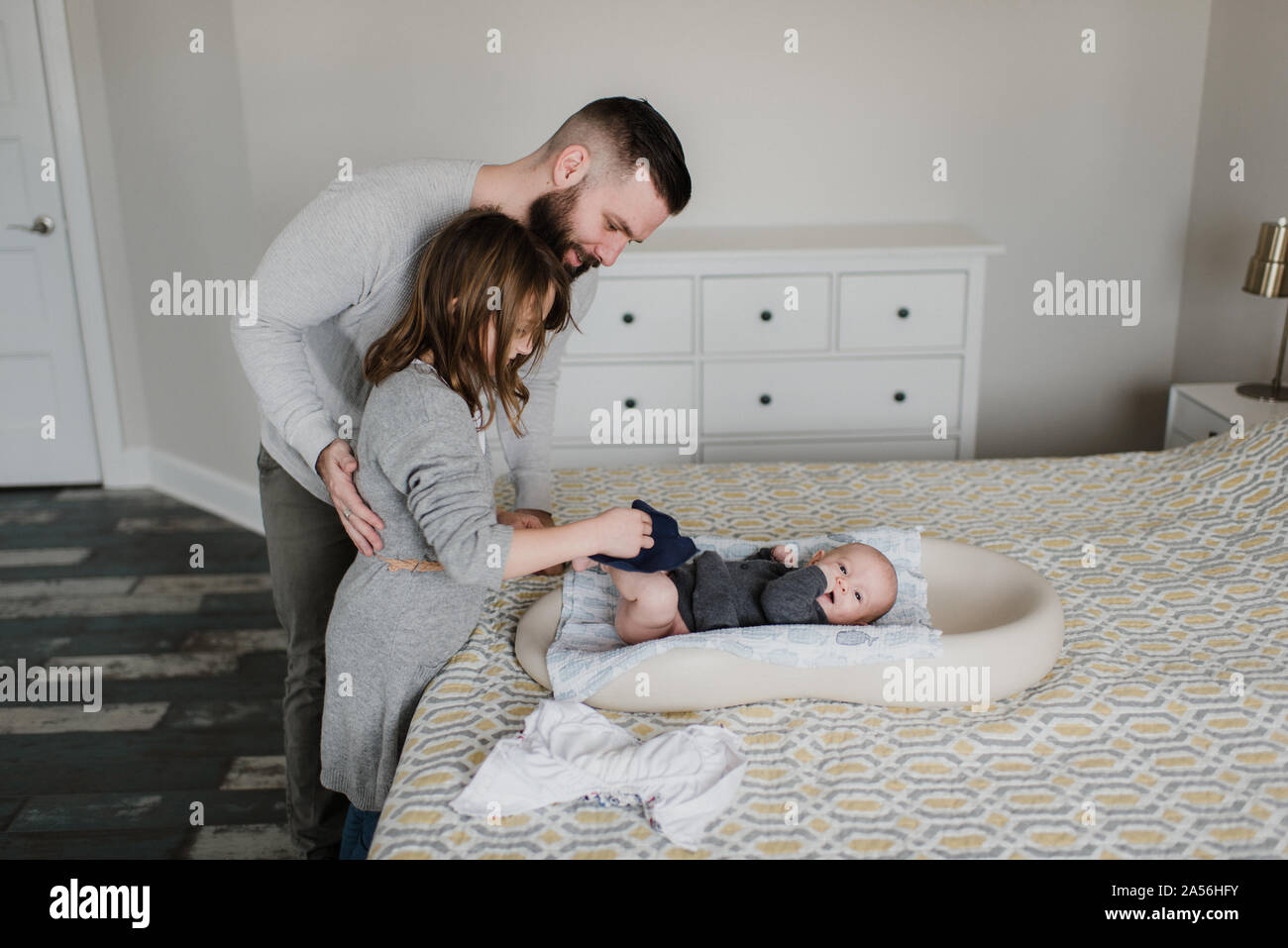 Ragazza con padre modifica baby fratello del pannolino sul letto, vista laterale Foto Stock