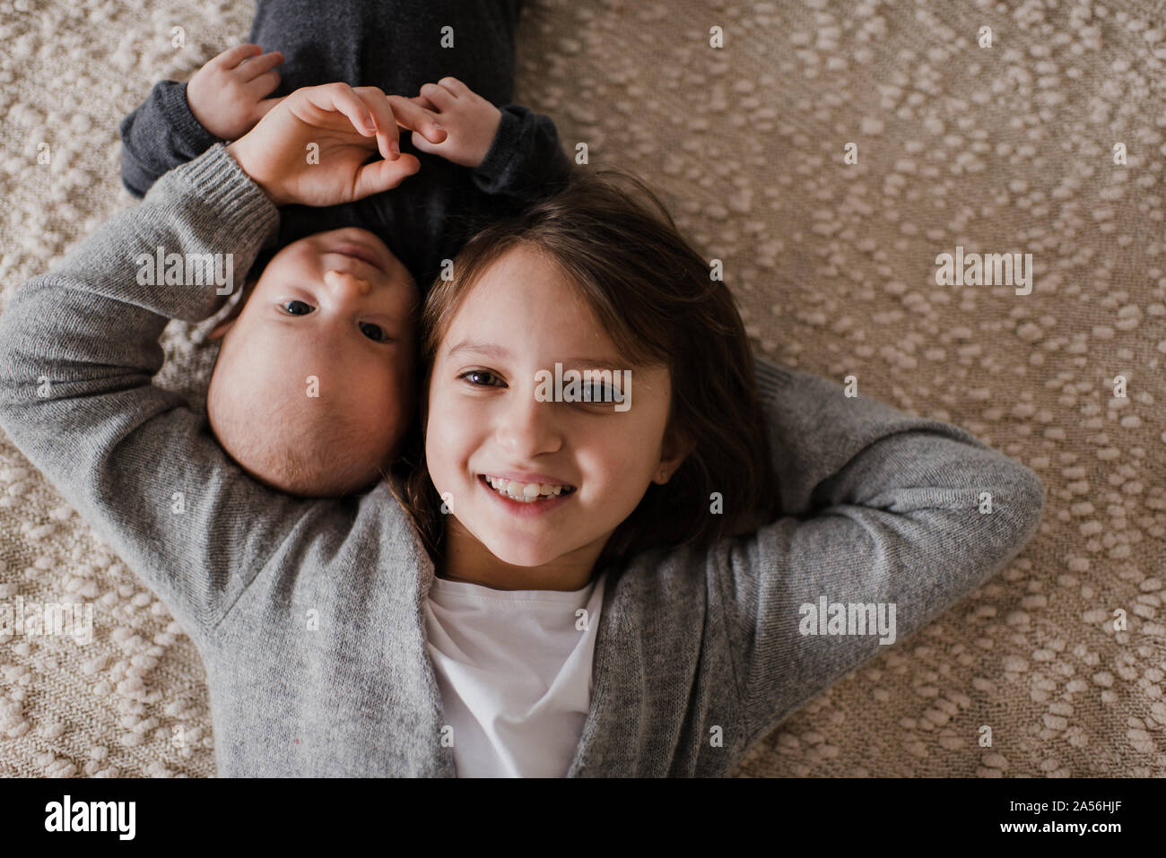 Ragazza distesa guancia a guancia con il fratellino sul letto, ritratto di overhead Foto Stock