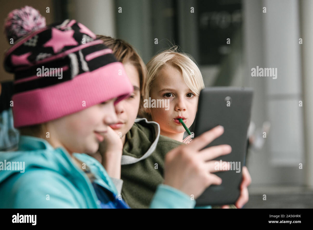 Ragazza e fratelli guardando digitale compressa in aeroporto, testa e spalle Foto Stock
