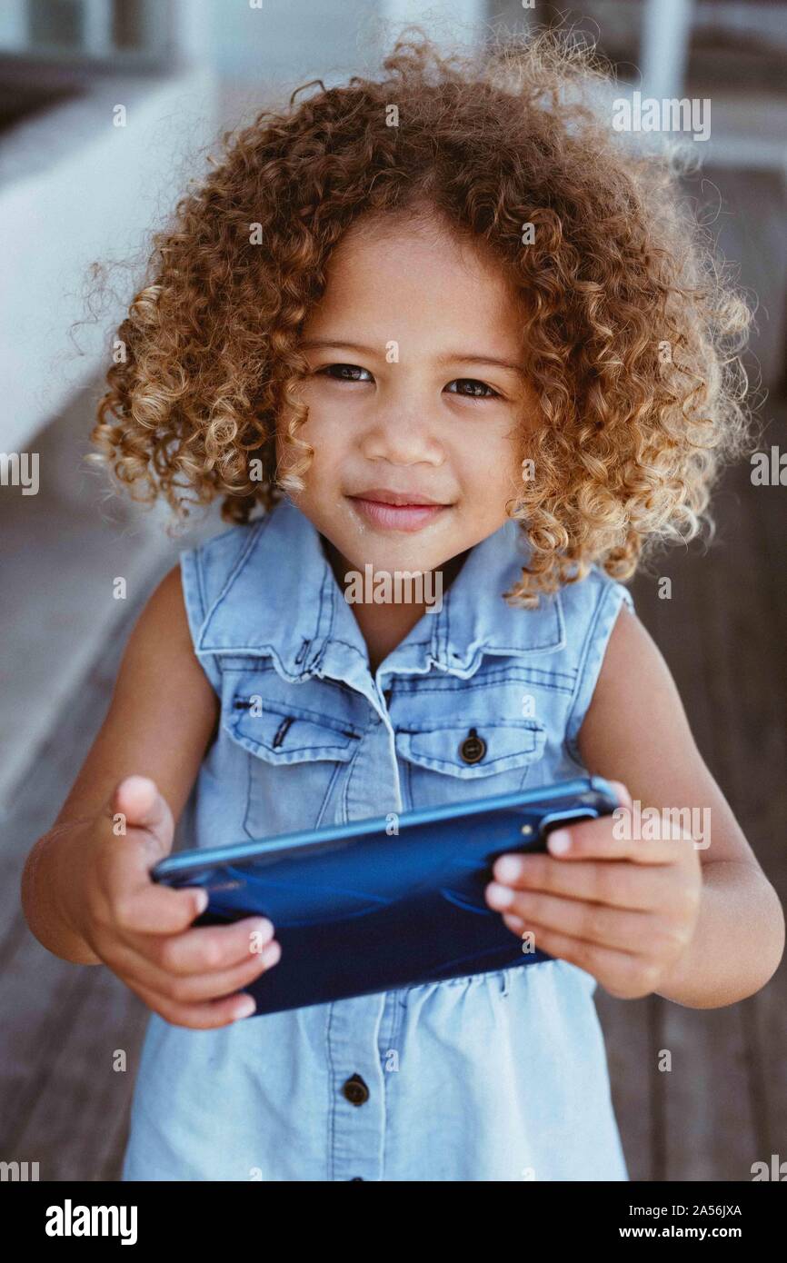 Bambina utilizza lo smartphone sul portico Foto Stock
