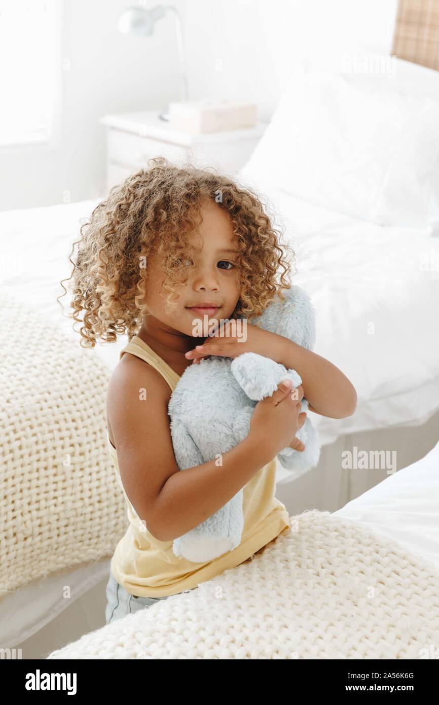 Bambina cuddling giocattolo morbido in camera da letto Foto Stock