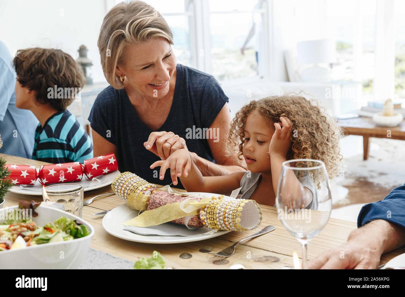 Donna che parla al nipote giocare con Christmas Cracker al tavolo da pranzo Foto Stock