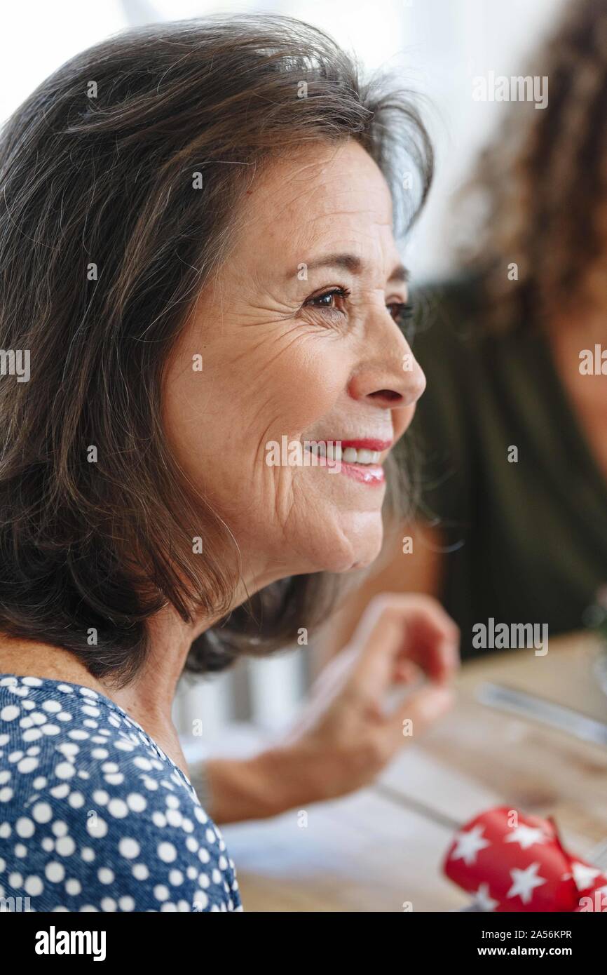 Senior donna ascolto attento al tavolo da pranzo Foto Stock