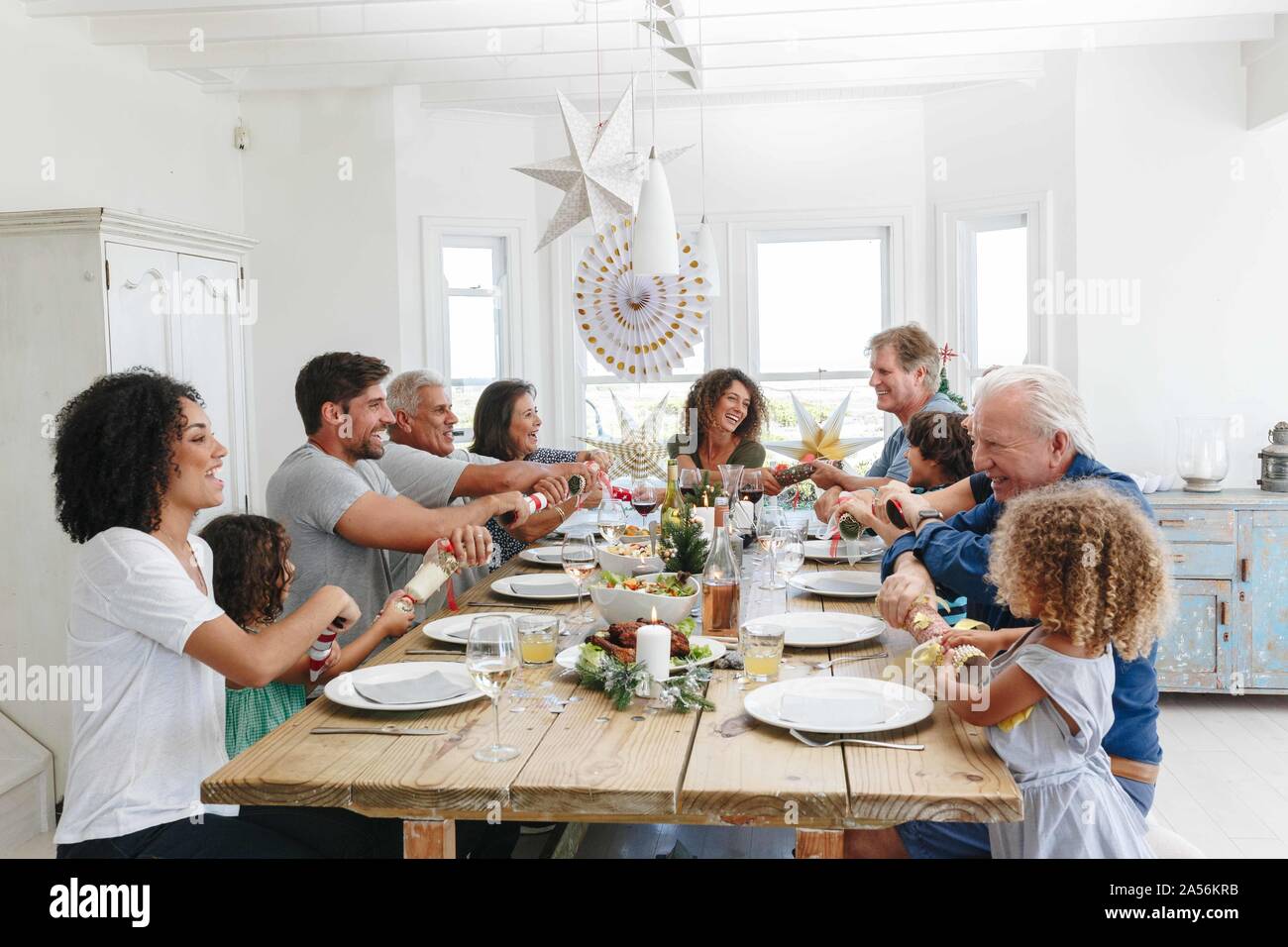 Famiglia popping Christmas Cracker insieme al tavolo da pranzo Foto Stock