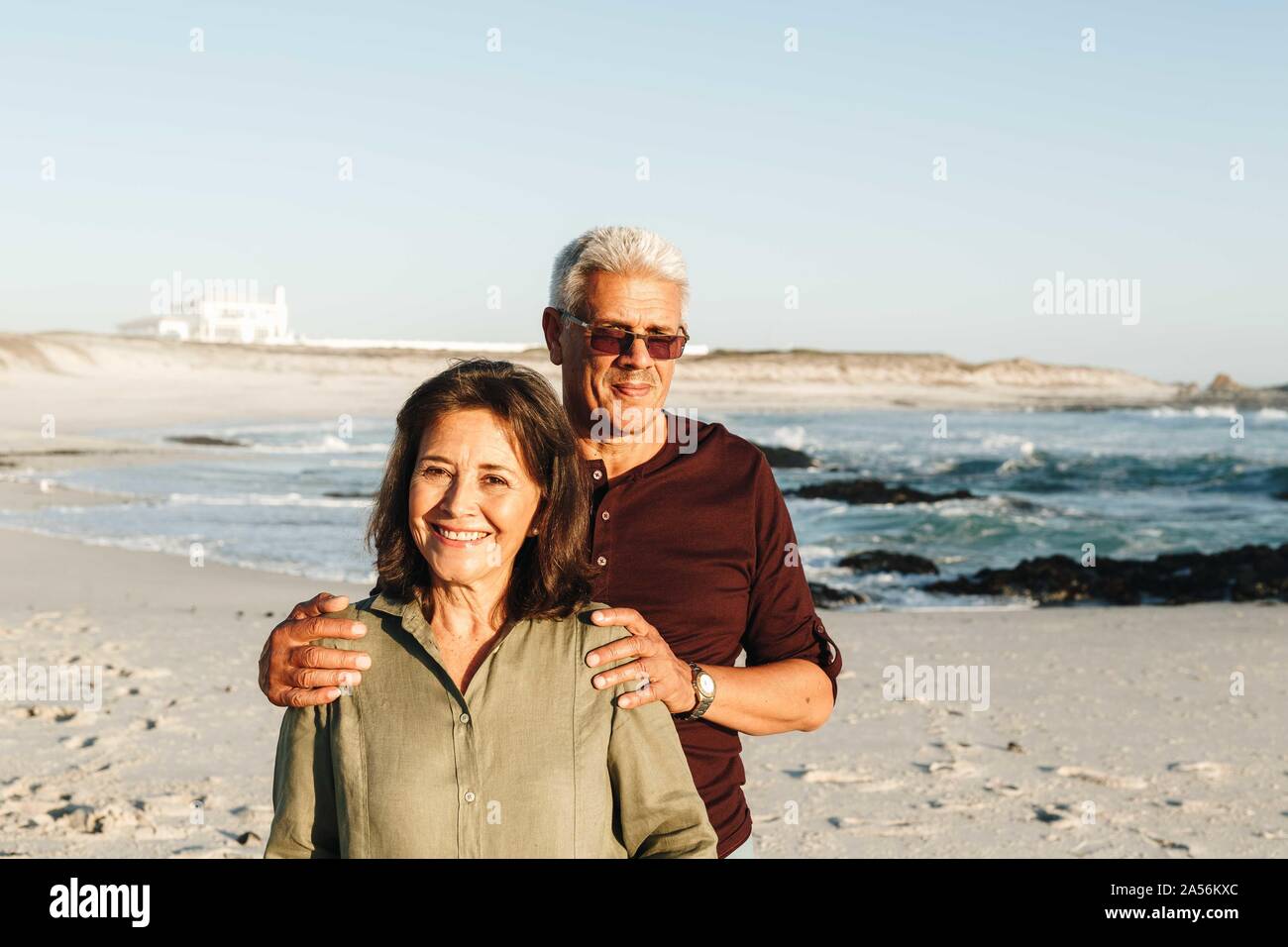 Coppia senior godendo di sole sulla spiaggia sabbiosa Foto Stock