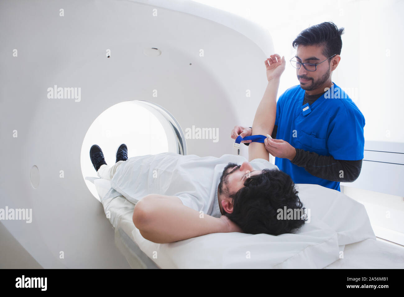 Giovane maschio radiologo preparazione paziente di sesso maschile per CT scan nel reparto di radiologia Foto Stock