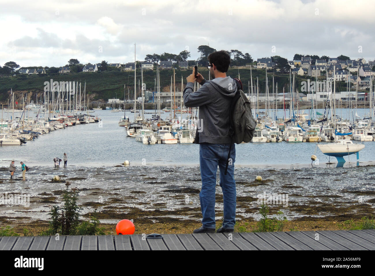 Camaret-sur-Mer, Francia. Giovane fotografo in fron delle barche e navi della marina Foto Stock