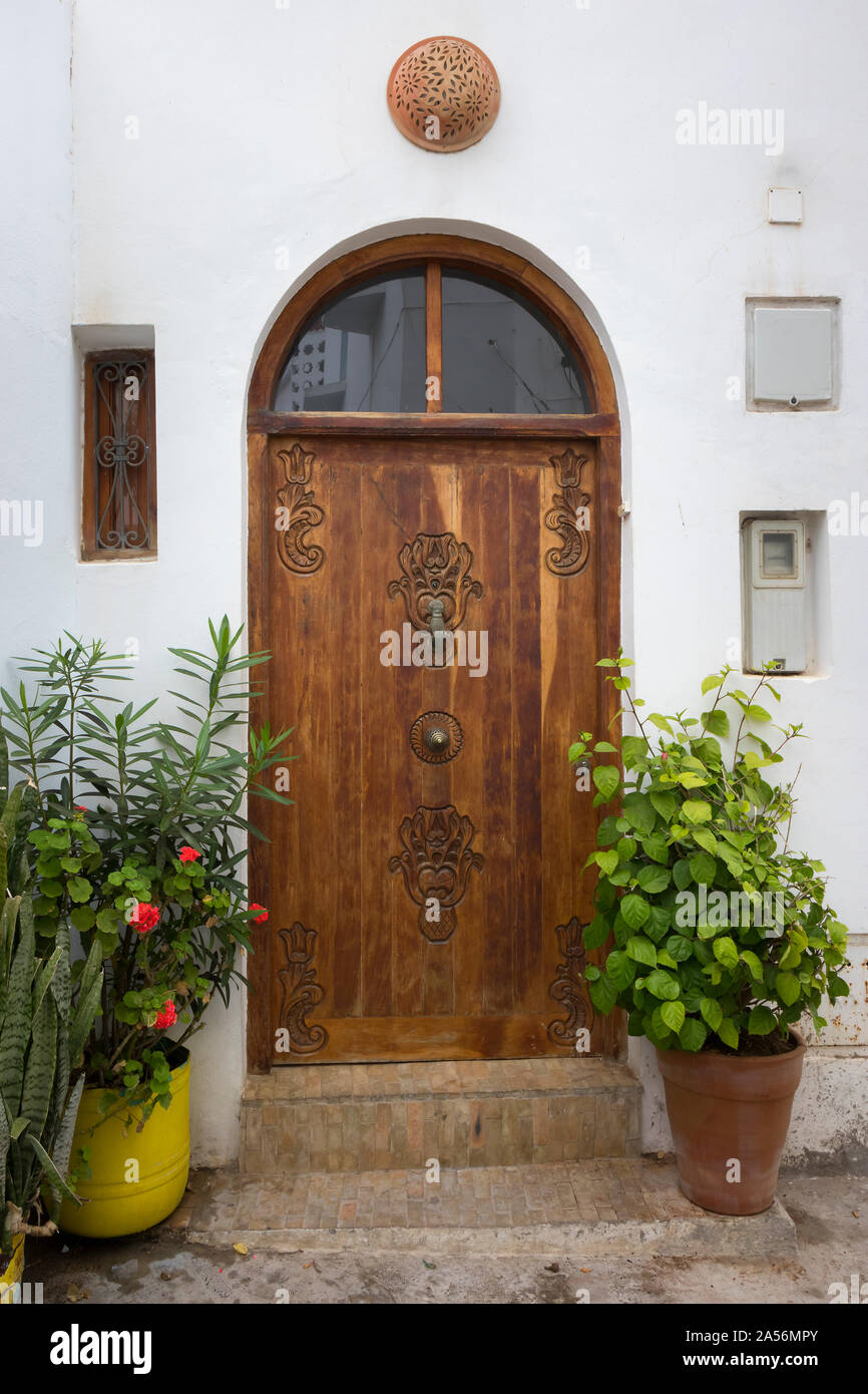 Vecchia decorata in legno porta con respingente in la forma di una mano in Asilah, Marocco Foto Stock