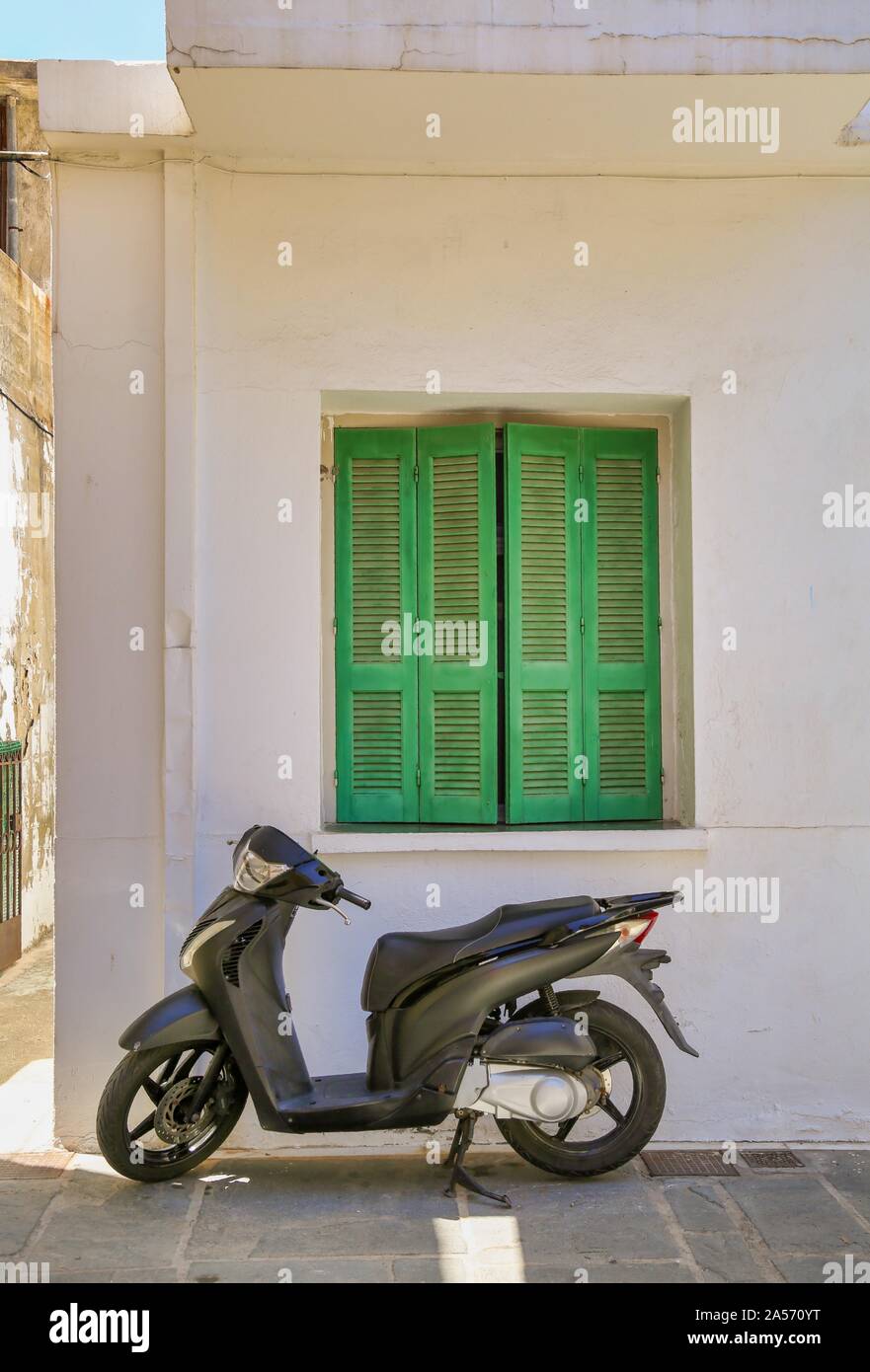 Un nero scooter e persiane verdi Foto Stock