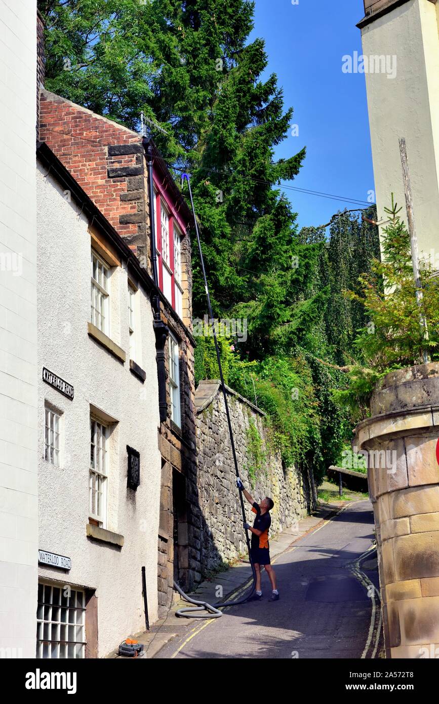 Un uomo con un leggero telescopico pulitore di gronda detriti più chiara in foglia,Matlock Bath,Derbyshire,l'Inghilterra,UK Foto Stock