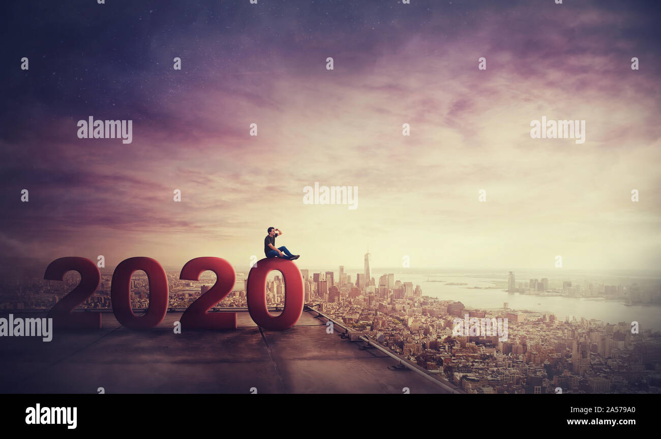 Uomo in attesa di successo seduti sul tetto di un grattacielo che si affaccia su un orizzonte di Città, 2020 numeri grandi che simboleggia il nuovo anno a venire. Trasognata guy Foto Stock