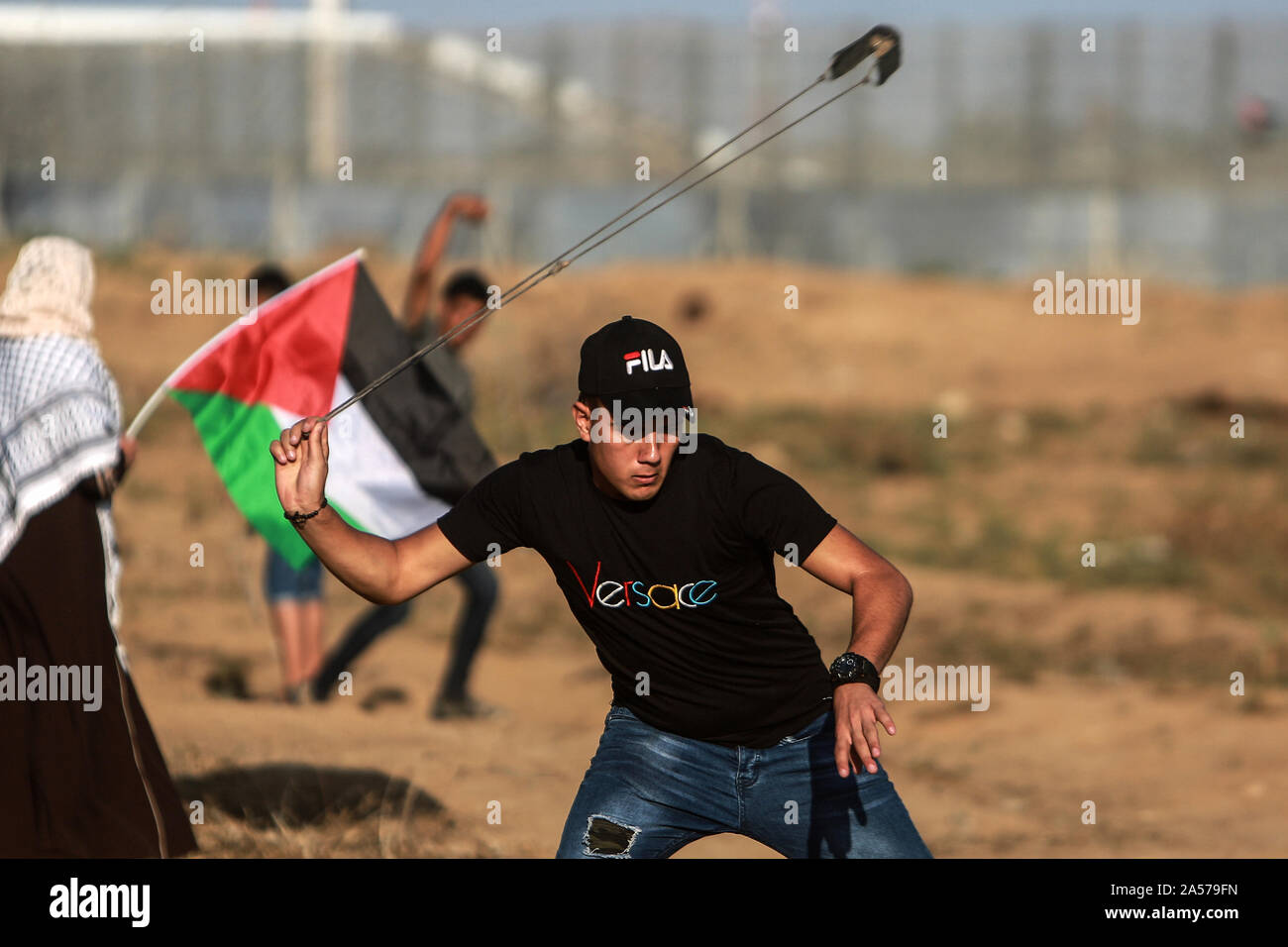 La striscia di Gaza. Xviii oct, 2019. Un manifestante palestinese utilizza un slingshot per scagliare pietre contro le truppe israeliane durante gli scontri sul confine Gaza-Israel, a est di Gaza City, 18 ottobre 2019. Almeno 69 palestinesi sono stati feriti il venerdì da soldati israeliani' cannonate durante gli scontri con decine di dimostranti palestinesi nella parte orientale della striscia di Gaza, vicino alla frontiera con Israele, i medici hanno detto. Credito: Mohammed Dahman/Xinhua/Alamy Live News Foto Stock