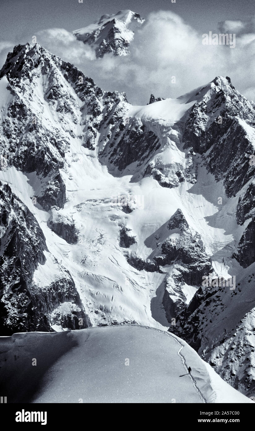 La minuscola figura di un alpinista sulla Aiguille de Midi con le montagne delle Alpi al di là Foto Stock