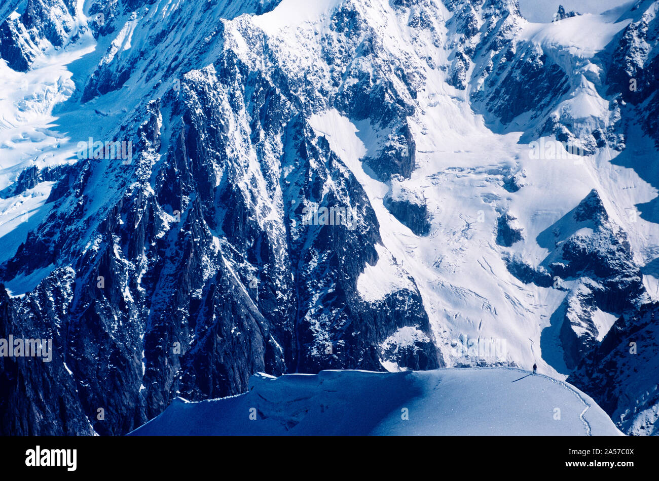 La minuscola figura di un alpinista sulla Aiguille de Midi con le montagne delle Alpi al di là Foto Stock