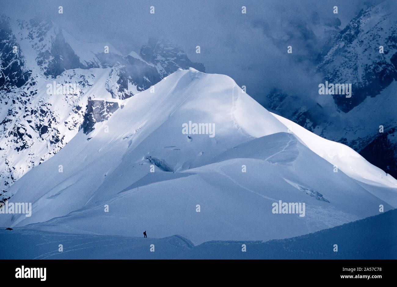 La minuscola figura di un alpinista sulla Aiguille de Midi con le montagne delle Alpi al di là Foto Stock