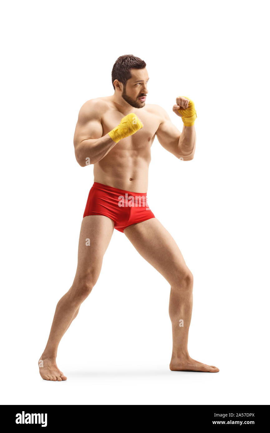 A piena lunghezza shot forte di un giovane uomo in pantaloncini rossi esercizio di kickboxing isolati su sfondo bianco Foto Stock