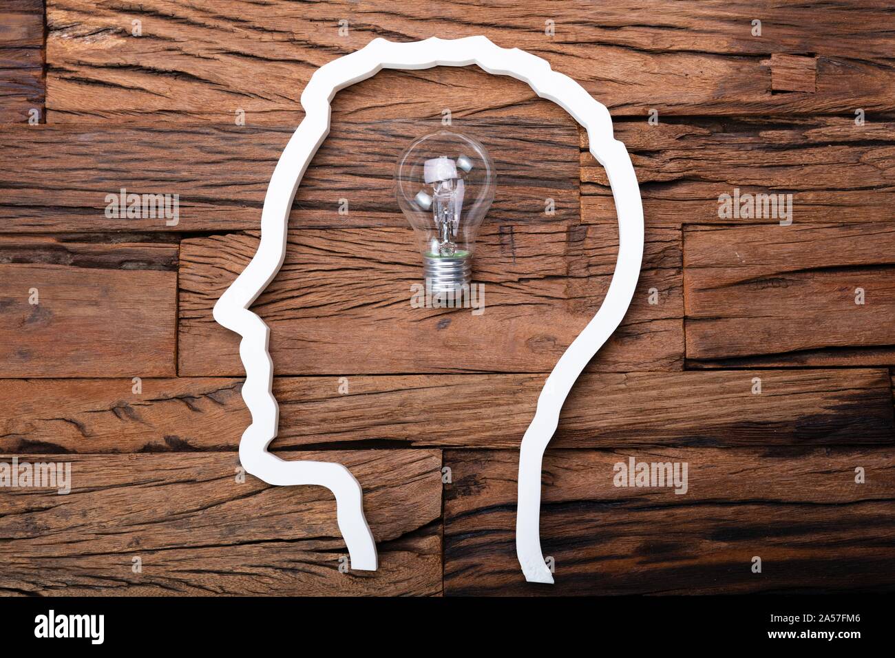 Lampadina idea all'interno di Silhouette di testa sulla scrivania in legno Foto Stock