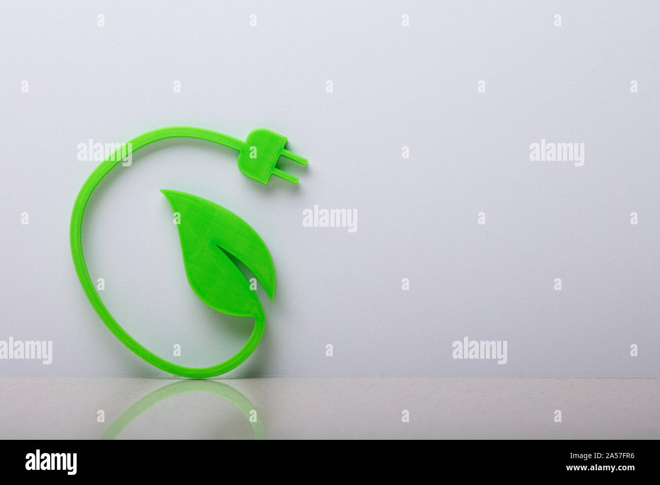Close-up di una energia verde simbolo appoggiata sul muro bianco Foto Stock