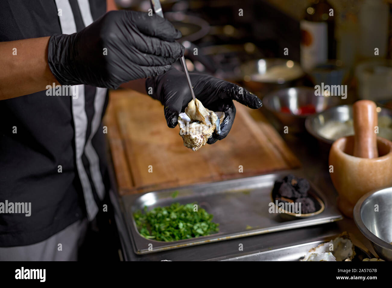 Concetto di cibo. Lo Chef prepara le ostriche per un piatto su un tavolo in cucina. Il processo di cottura di spaghetti con frutti di mare. Close up Foto Stock