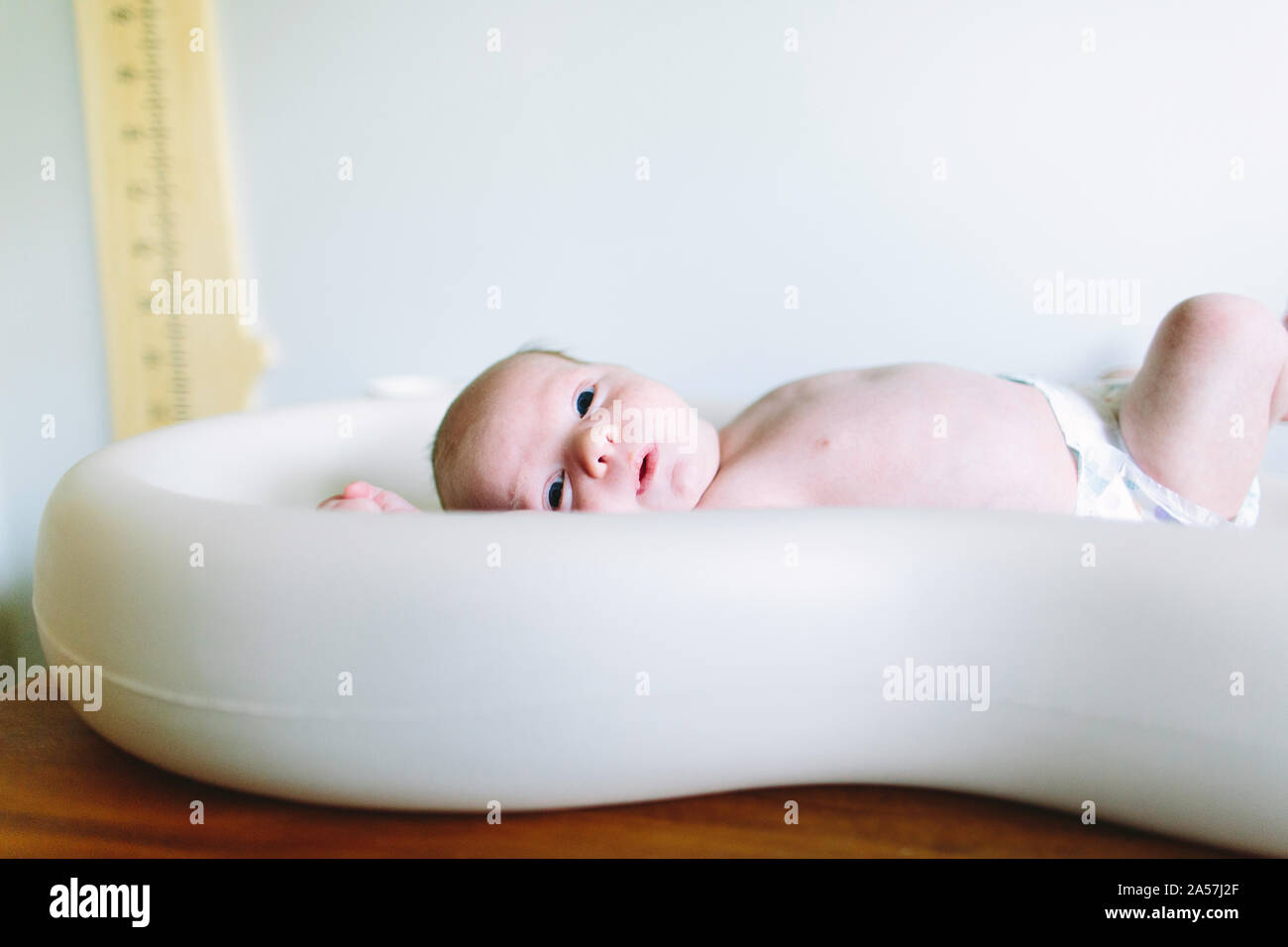 Vista laterale di un neonato ragazzo posa su una modifica tabella Foto Stock