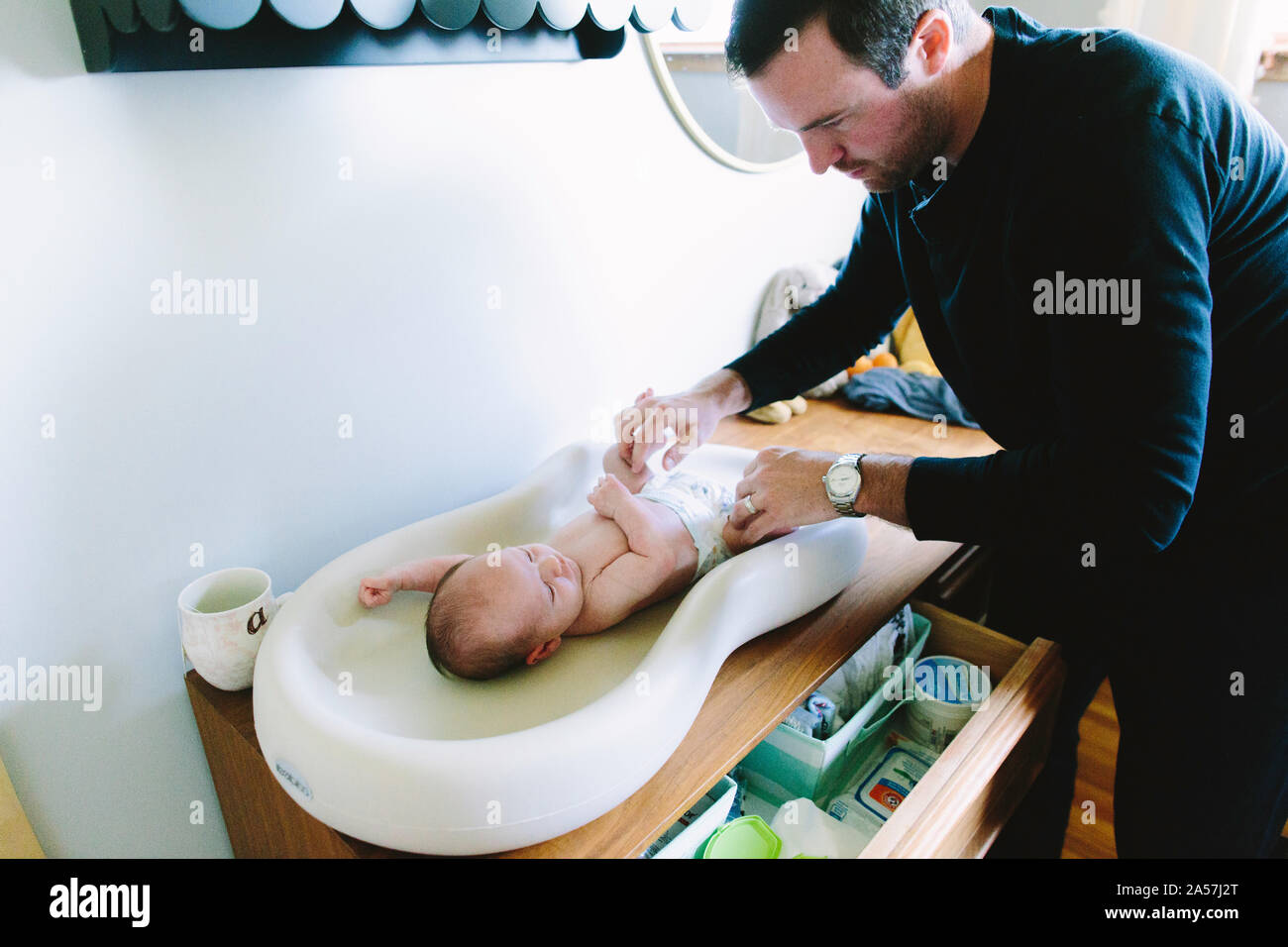 Un nuovo papà cambia i suoi neonati pannolino su una modifica tabella Foto Stock