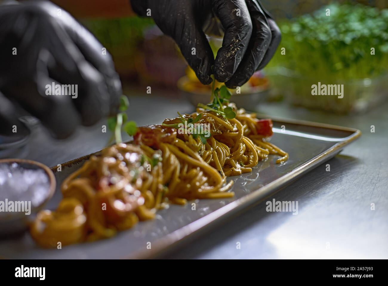 Concetto di cibo. Lo chef è decorata con erbe aromatiche e fiori piatti nel ristorante. Il processo per la fabbricazione di spaghetti con frutti di mare. Foc selettiva Foto Stock