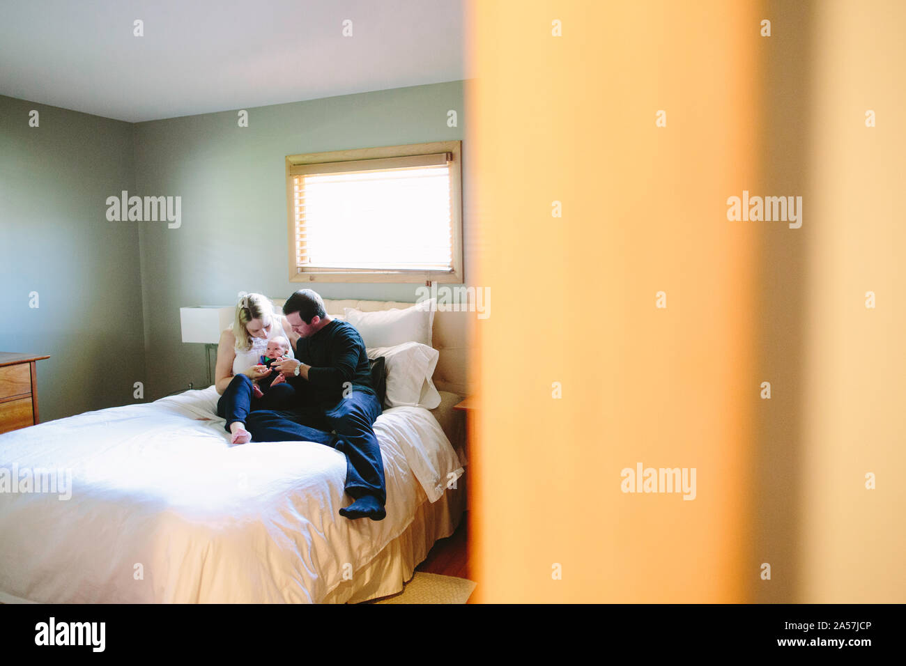La vista dalla sala di una famiglia seduta su di un letto con loro nascente bab Foto Stock