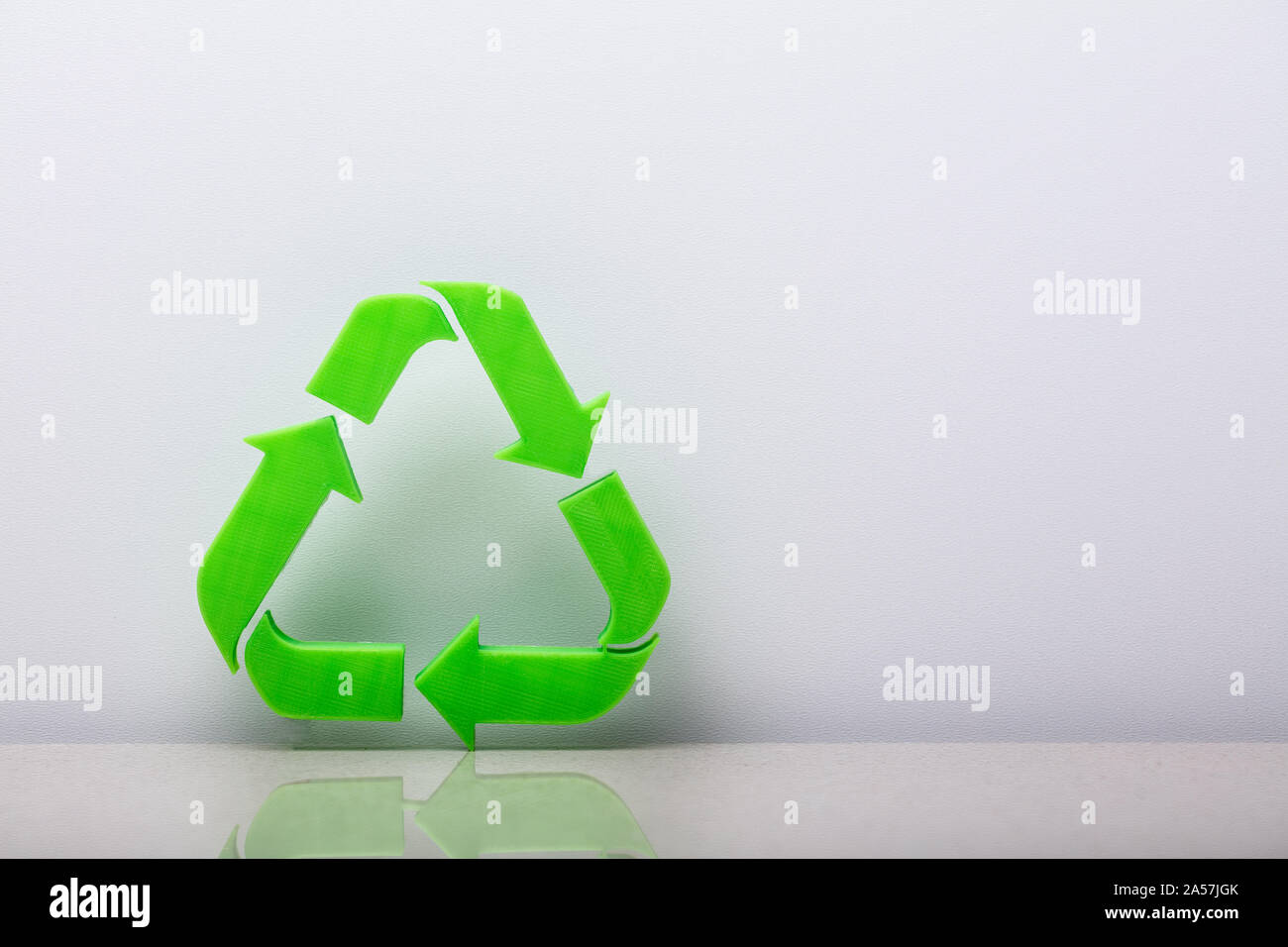 Close-up di un simbolo di riciclaggio appoggiata sul muro bianco Foto Stock