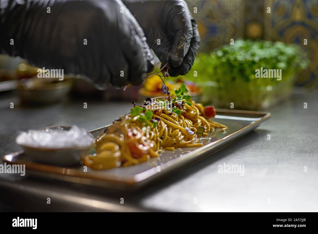 Concetto di cibo. Lo chef è decorata con erbe aromatiche e fiori piatti nel ristorante. Il processo per la fabbricazione di spaghetti con frutti di mare. Foto Stock