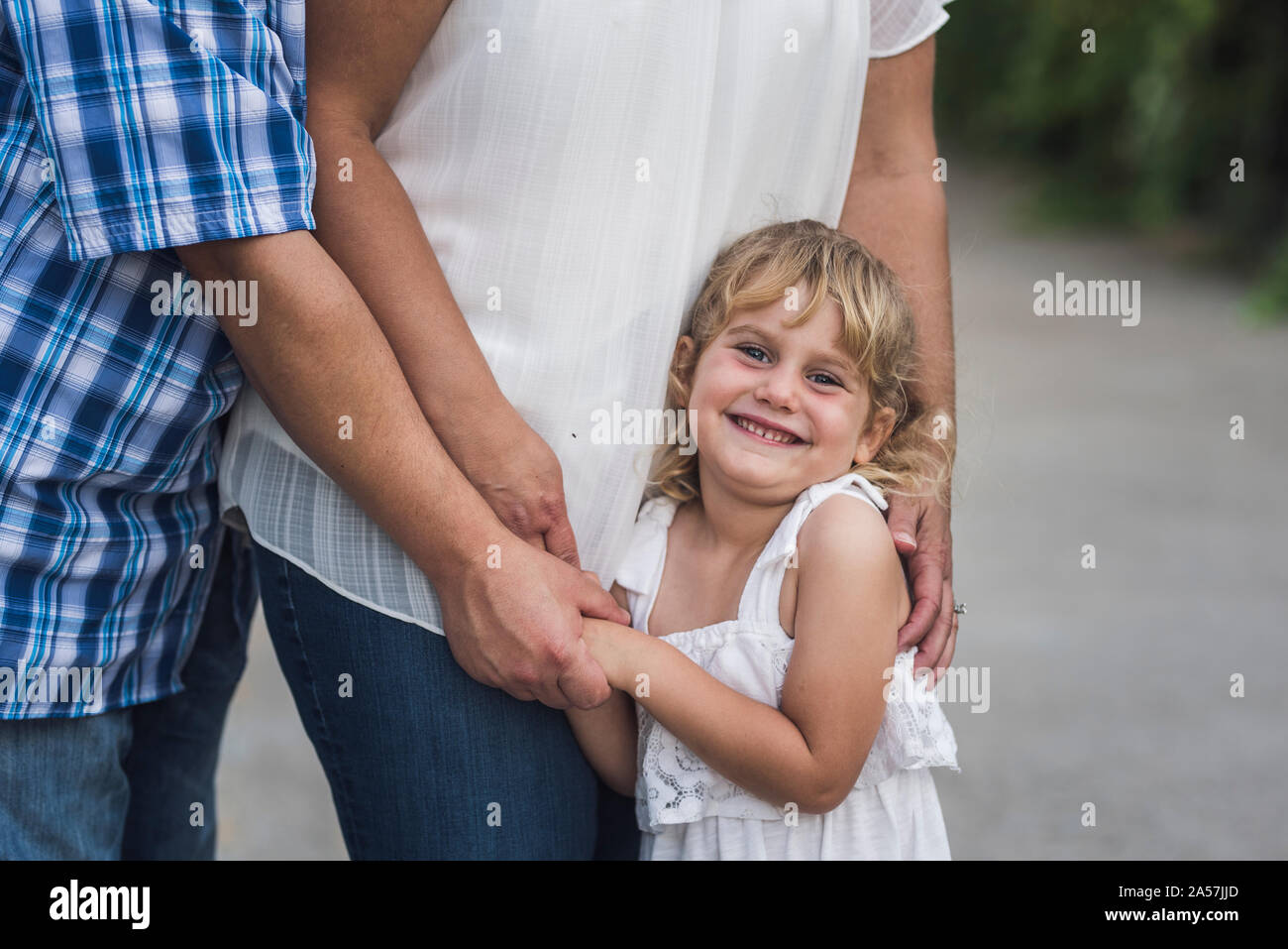Dolce sorridente ragazza bionda abbracciando la sua mamma e papà Foto Stock