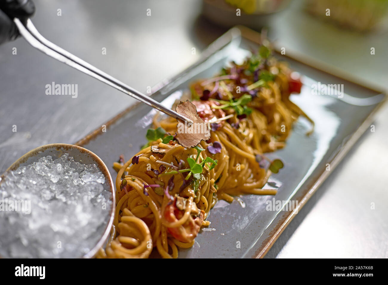 Concetto di cibo. Lo Chef decora piatti con fettine di tartufo. Il processo per la fabbricazione di spaghetti con frutti di mare. Foto Stock