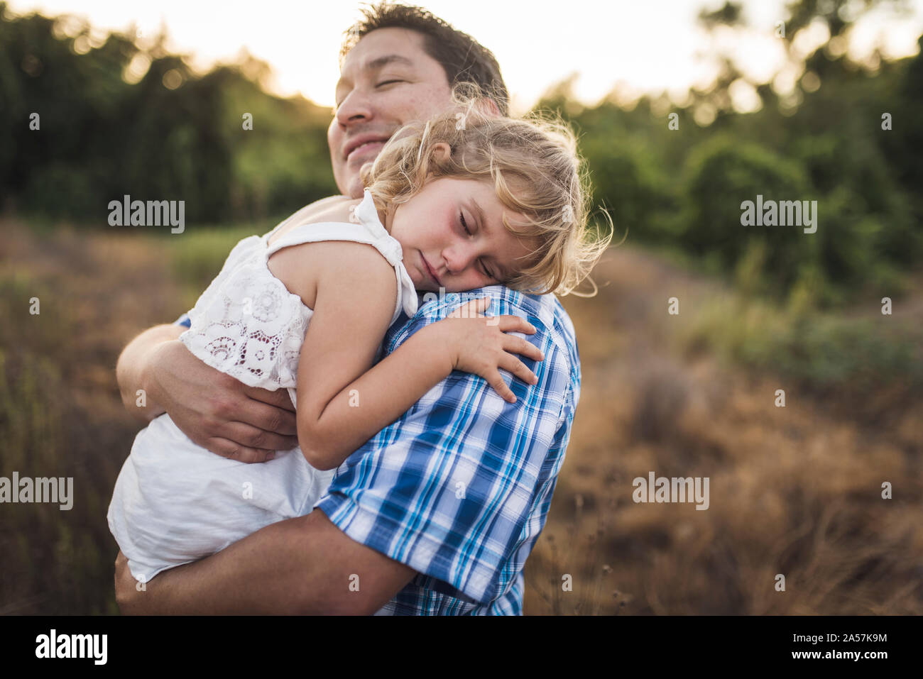 Papà sorridente coccole bambino che dorme sulla sua spalla Foto Stock