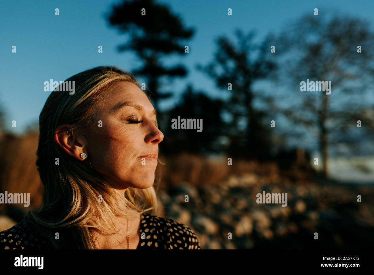 Donna pacifica con gli occhi chiusi sulla spiaggia al tramonto Foto Stock