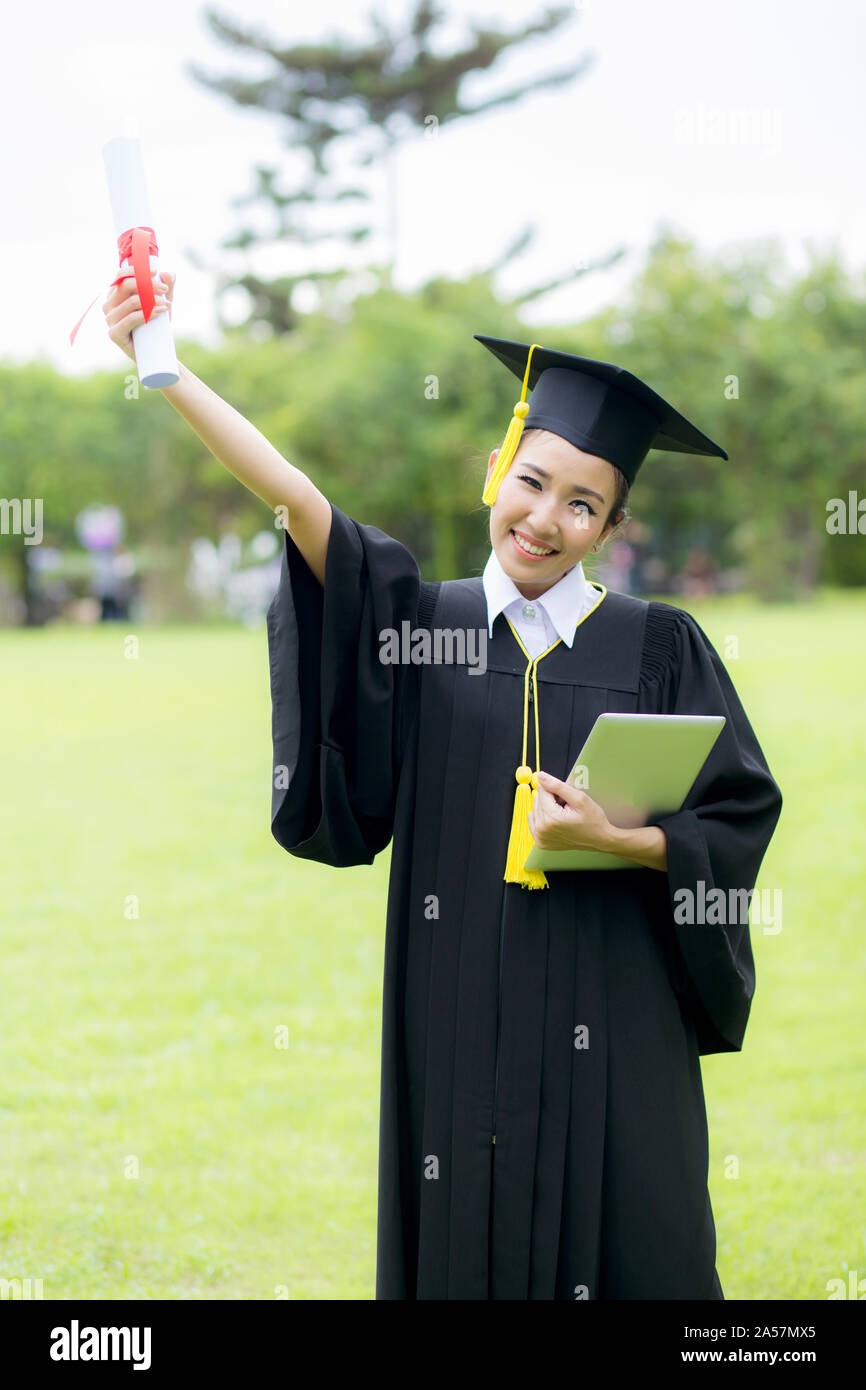 Laurea studenti donna indossa la laurea hat e vestaglia e azienda tablet Foto Stock