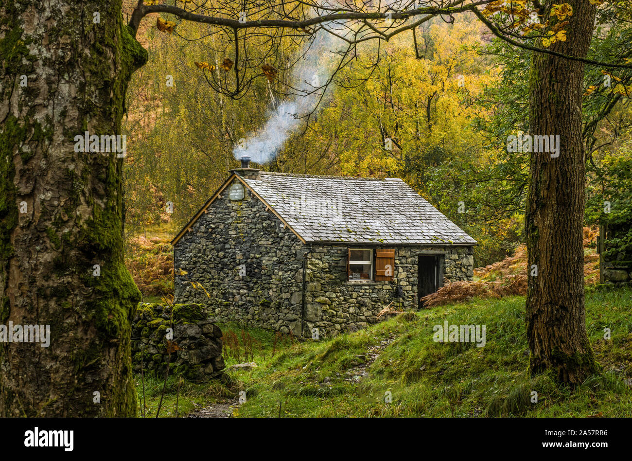 Capanna di pietra con il fumo del camino vicino Ponte Ashness nel Parco Nazionale del Distretto dei Laghi in autunno Foto Stock
