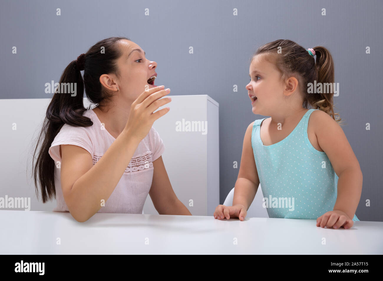 Un attraente femmina Logopedista aiuta la ragazza come pronunciare i suoni in Office Foto Stock