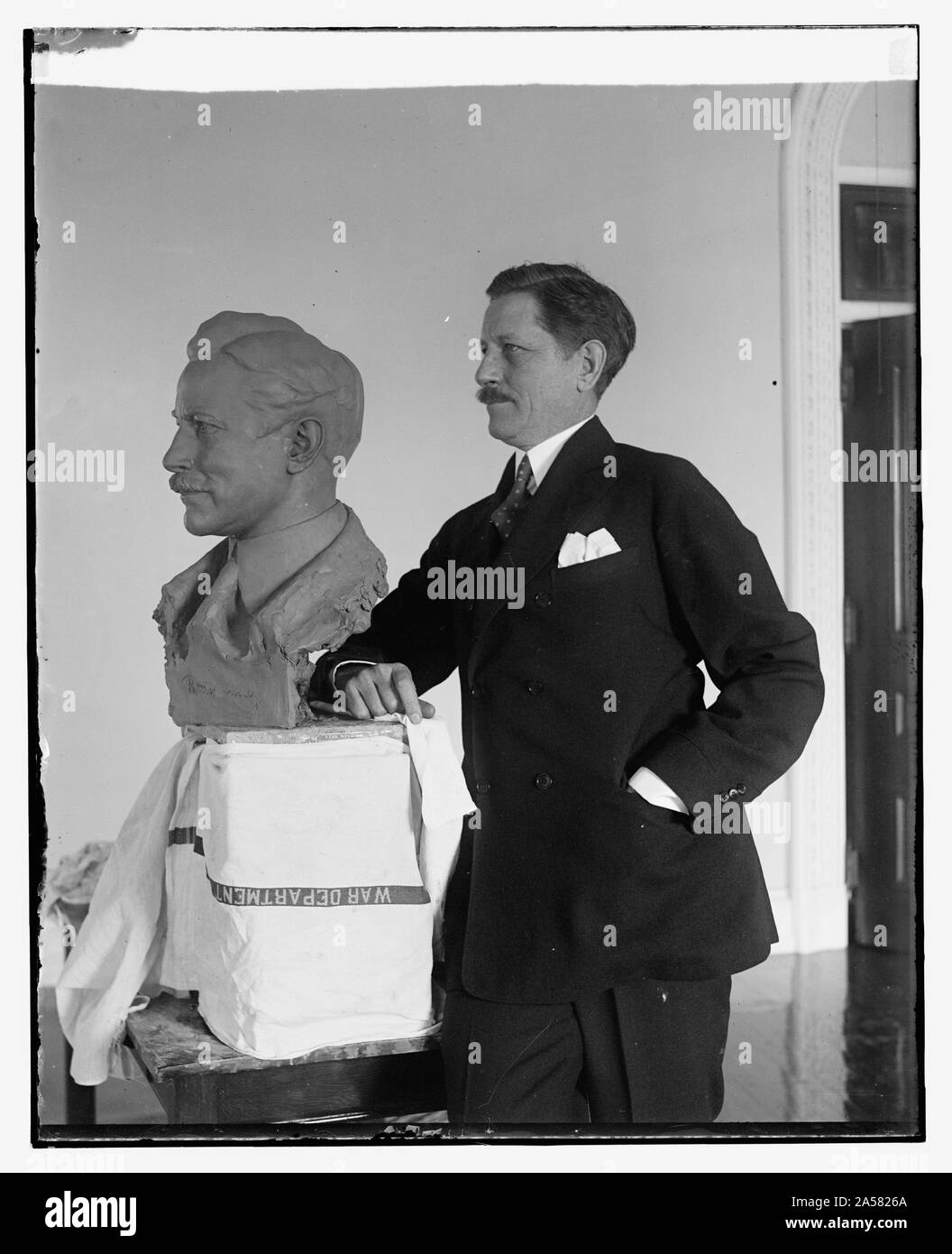 Segretario di guerra pone per il busto di noti scultore. Il segretario della guerra Patrick J. Hurley in posa per il tocco finale di un busto di se stesso che è in via di completamento per le mani di Edgardo Simone, notato scultore italiano, che è stata la modellazione di un certo numero di personaggi di spicco nel suo studio di Washington Foto Stock