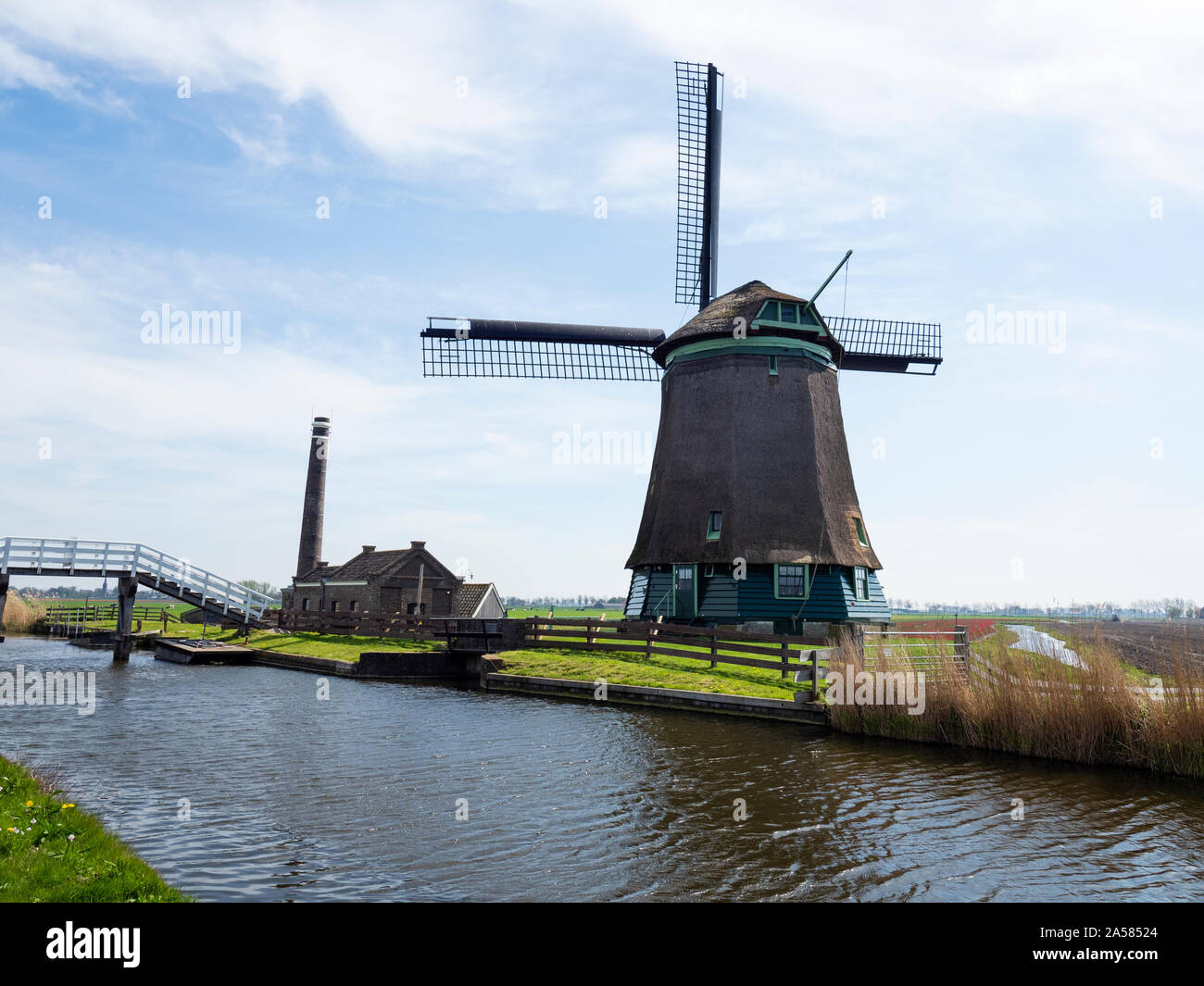 Rurale scena con mulino a vento e Old Bakery sulla riva del canal, Oude Niedorp, North Holland, Paesi Bassi Foto Stock