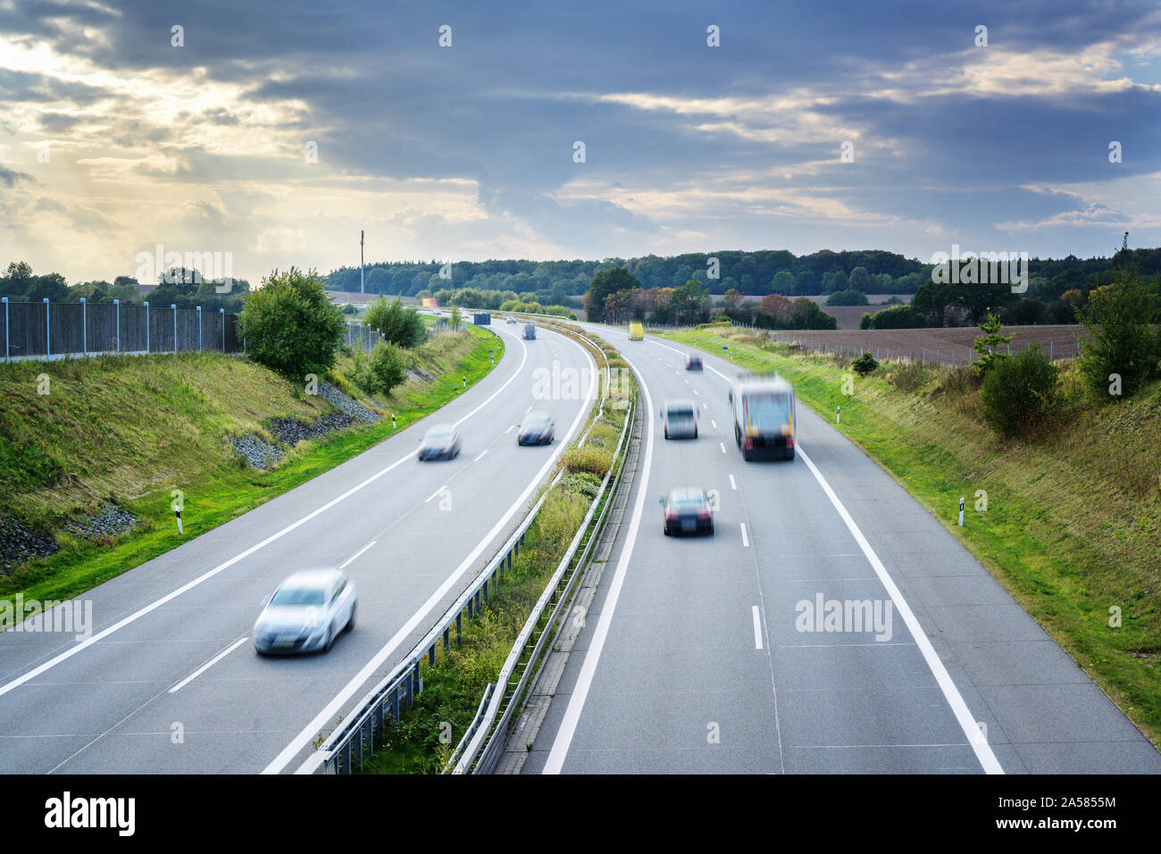 Autostrada del paese con la guida di automobili e camion in motion blur, concept per il traffico, il trasporto e la protezione ambientale, copia dello spazio nel cielo con c Foto Stock