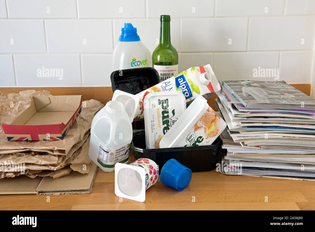 Articoli per la casa sul piano cucina pronti per il riciclaggio inclusa la plastica, carta, cartone e vecchi cataloghi. Foto Stock